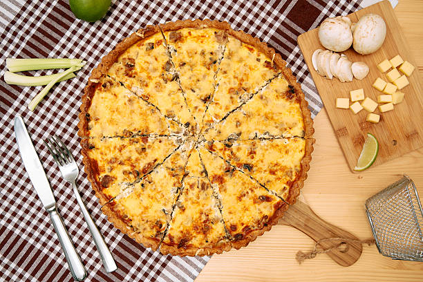 istock Cheese mushroom quiche on checkered tablecloth with ingredients displayed 2225063615