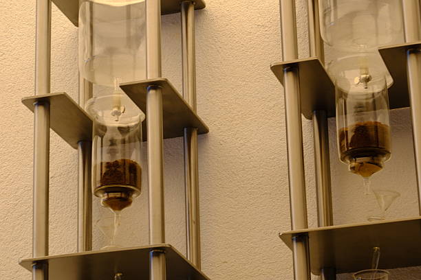 Close-up and general views of a cold brew tower hanging on a wall in a cafe. A device that brews cold brew using filter coffee and ice cubes using distillation. Enjoying coffee. Cafe culture.