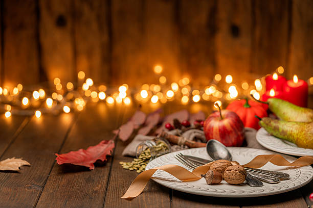 Cozy Autumnal vintage place setting on rustic table. Fruits, pumpkins and nuts with fallen leaves. Thanksgiving decoration on illuminated background