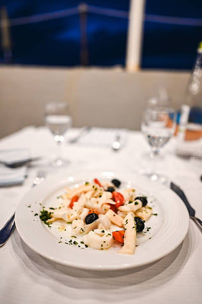 Delicious seafood salad with squid, tomatoes, and olives served on a restaurant table
