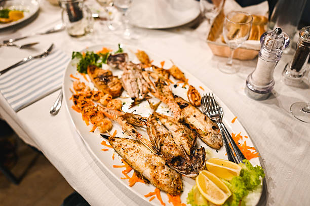 Grilled fish platter with shrimp, lemon, and parsley on restaurant table
