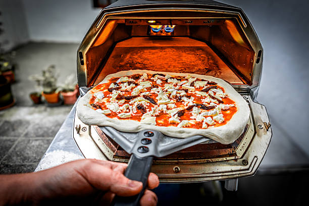 istock Gently placing the raw pizza, already covered with its toppings, into the oven to begin its perfect cooking. 2225074033