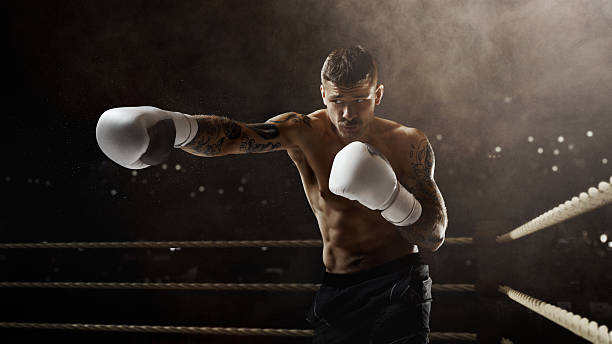 istock Tattooed boxer with white gloves strikes forward with power on a 3D boxing ring. 2225074144