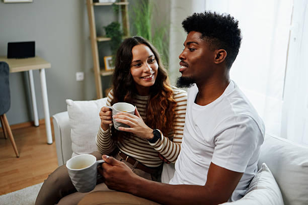 istock Happy couple relaxing on sofa, drinking coffee and enjoying conversation at home 2225074396