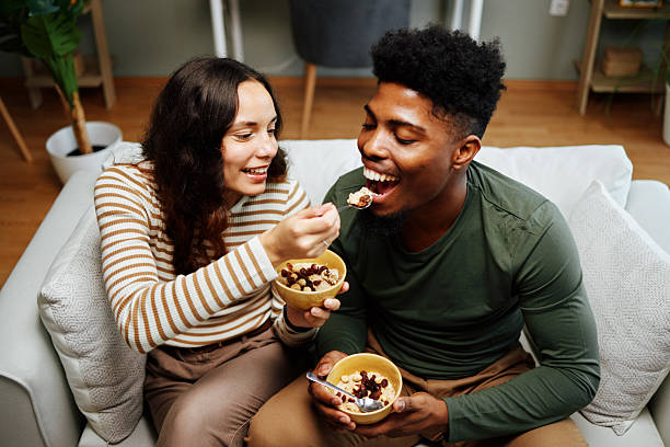 A beautiful & happy mixed-race couple, multiracial and black, enjoying a barbecue brunch made of fried chicken, French fries, fresh tomato and green salad, salad with figs and spinach, showing positivity and happiness, sharing and representing love, joy, wellbeing, true couple friendship, security, trust and togetherness