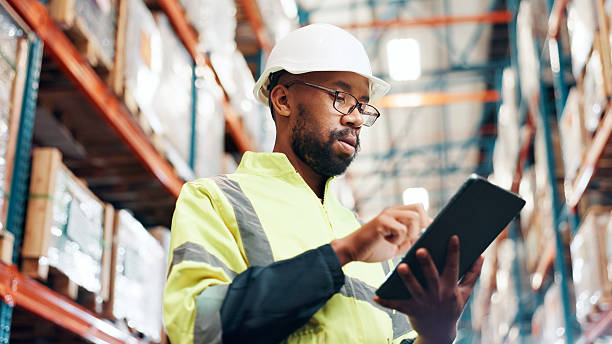 istock Distribution, below and man with tablet in warehouse, quality assurance and inventory management. Digital checklist, logistics and African inspector in factory for stocktaking on tech with shipping 2225077982