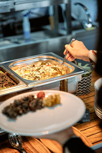 istock Buffet dining experience: person serving from stainless steel chafing dish 2225080230