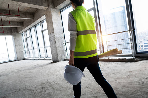 istock Female engineer holding blueprints walking on construction site 2225082222