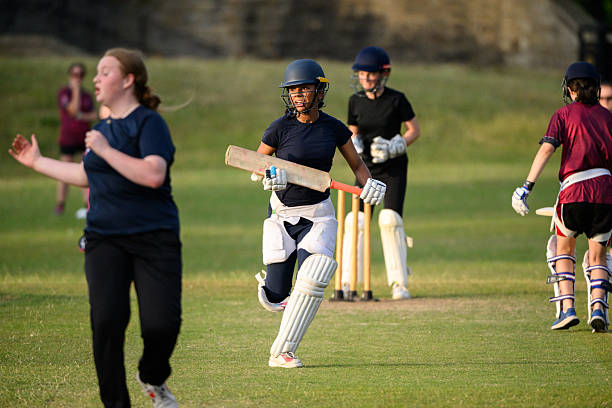 Female batter running between the wickets scoring a run during cricket game