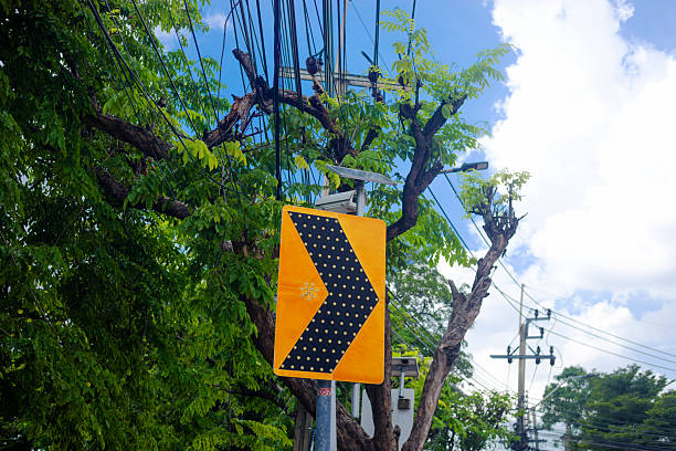 Right turn road sign with solar panel and CCTV cameras behind in front of trees in Bangkok