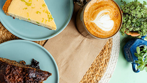istock Delicious cappuccino, lime cheesecake and chocolate cake served on a table with plants 2225088663