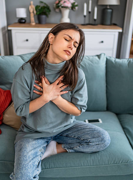 istock Young woman suffering chest pain while sitting on sofa 2225089180