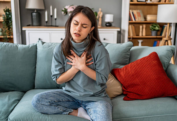 istock Young woman suffering chest pain while sitting on sofa at home 2225089201