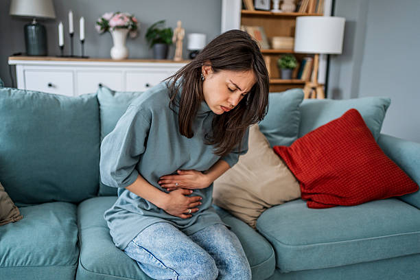 istock Young woman suffering from abdominal pain while sitting on sofa 2225089762