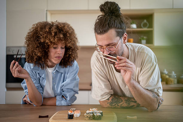 istock Couple smelling sushi with chopsticks in kitchen 2225091688