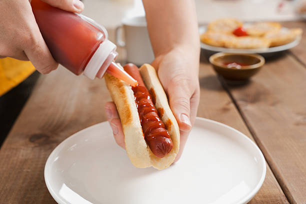 Hot dog with ketchup on a white plate. Close up.