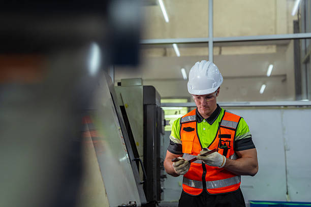 istock A man in a safety vest is looking at a computer screen. Machinist or CNC machine operator setting up a cutting tool for a milling machine in a metalworking factory. 2225093789