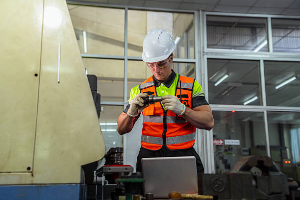 istock A man in a safety vest is working on a machine. Machinist or CNC machine operator setting up a cutting tool for a milling machine in a metalworking factory. 2225093797