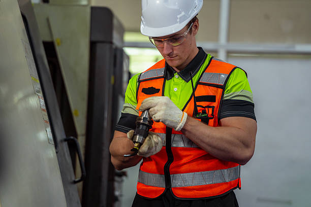 istock A man in a safety vest is working on a machine. Machinist or CNC machine operator setting up a cutting tool for a milling machine in a metalworking factory. 2225093814