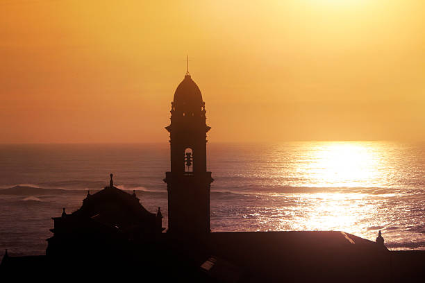 Santa María de Oia monastery at coastline by the beach and  Atlantic ocean. Rías Baixas, Pontevedra province, Galicia, Spain. Outlined at dusk, sunset background.