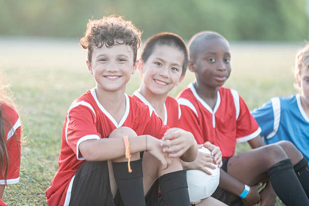 istock Happy Children in Soccer Uniforms Sitting on a Field During Practice 2225101533