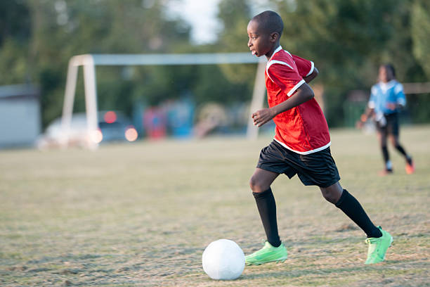 istock Boy in Red Jersey Playing Soccer on a Green Field 2225101543
