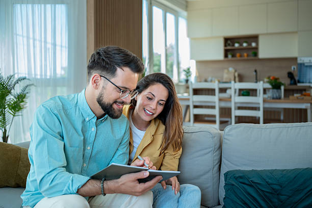 istock Young couple sitting on sofa, reading notes and planning future 2225101648