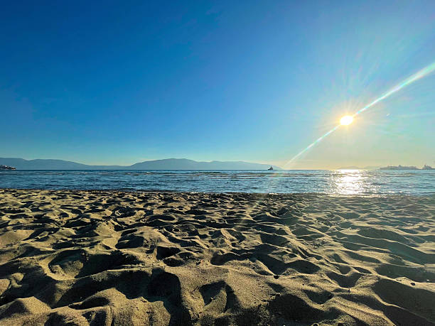 istock Sunlit coastal shoreline with soft sand, brilliant sky and distant waterline 2225103047