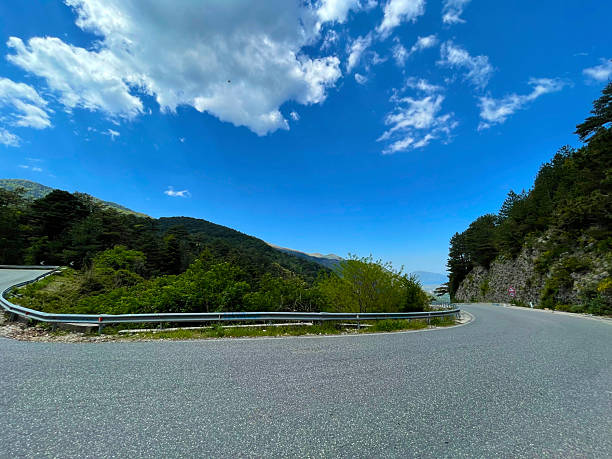 istock Scenic hillside landscape with curving road and tree-lined terrain under soft light 2225103161