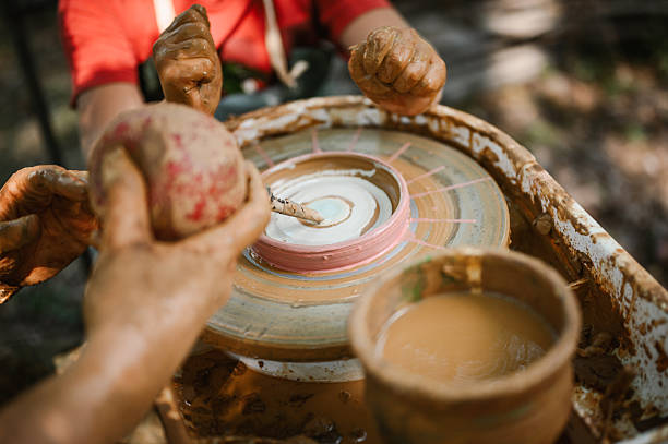 Child making earthenware cup/plate on pottery wheel. Kid learning pottery.