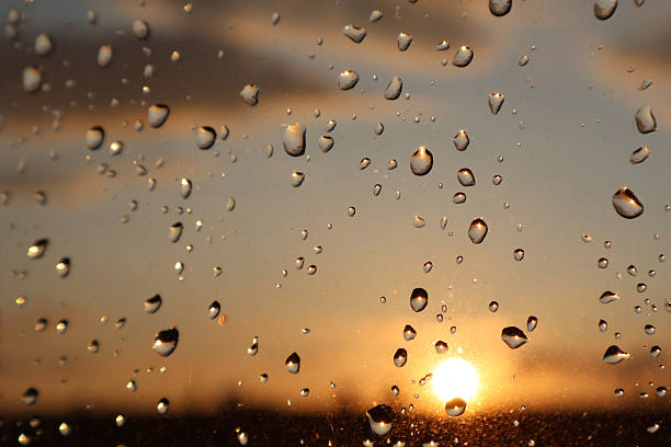 Witness the captivating sight of a sunset through shimmering raindrops on a window. The serene colors of the setting sun mix beautifully with the sparkling droplets, creating a picturesque and artistic scene. This image invites viewers to appreciate the delicate balance of light, water, and nature’s ever-changing canvas.