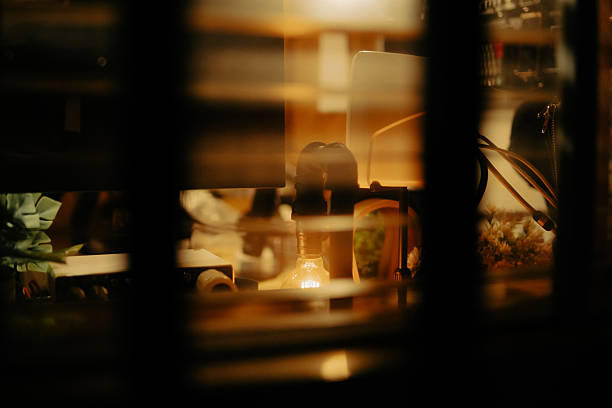 istock Warm Cinematic Desk Setup Viewed Through Window Blinds at Night 2225108395