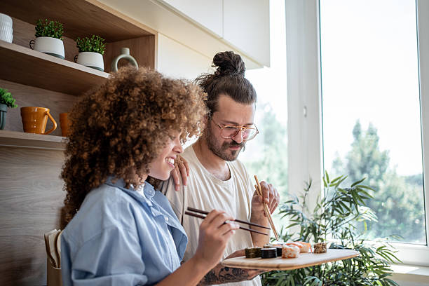 istock Young couple enjoying sushi together in their modern kitchen 2225112443