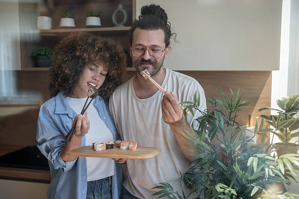 istock Young couple enjoying sushi together in their modern kitchen 2225112470
