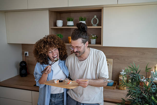 istock Happy couple eating sushi in modern kitchen 2225112476