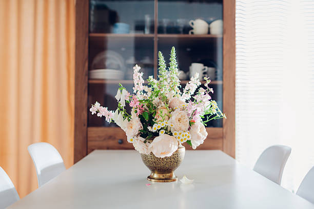 istock Interior decor. Summer flower arrangement made in brass vase put on dining table by cupboard. Bouquet with roses, foxgloves 2225114526