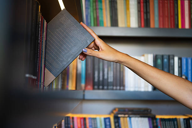 istock Woman’s Hand Reaching for a Book on Library Shelf 2225114654