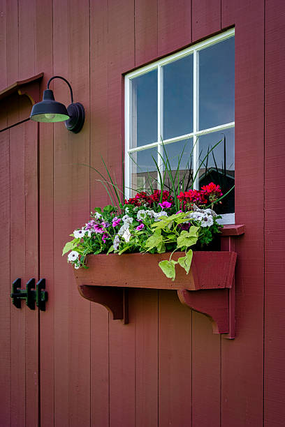 istock Rustic Window with Flower Box and Outdoor Barn Light on Red Siding 2225114847
