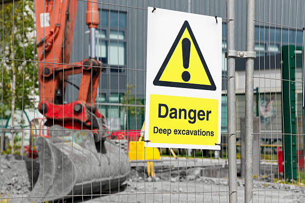 istock Deep excavations danger sign on fence with digger in background on construction site 2225118555