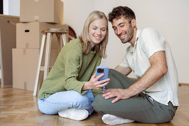 istock Young couple is using phone in their cozy new home 2225118694