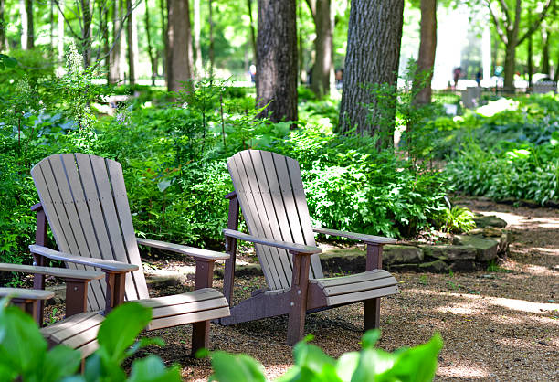 Outdoor chairs sit quietly in a serene park or garden setting, inviting rest and relaxation. Surrounded by greenery and natural light, this tranquil scene evokes a sense of calm, leisure, and connection with nature. Ideal for concepts of mindfulness, outdoor living, wellness, and peaceful moments.