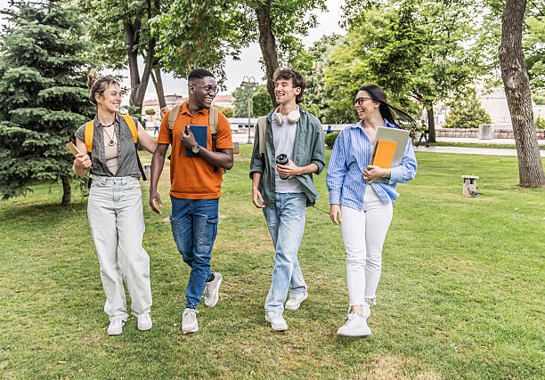 istock Cheerful university students walking and talking together in a park 2225122393
