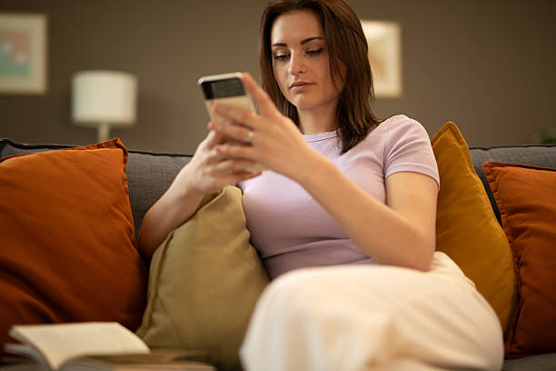 istock Young woman relaxing on sofa using smartphone at home. Stock image 2225126793