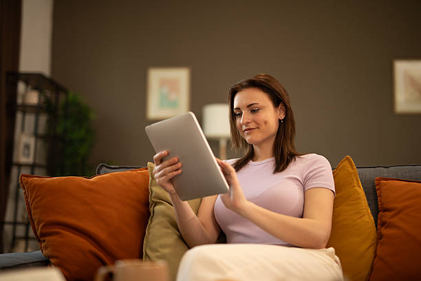 istock Young woman relaxing on sofa using digital tablet at home. Stock image 2225126799