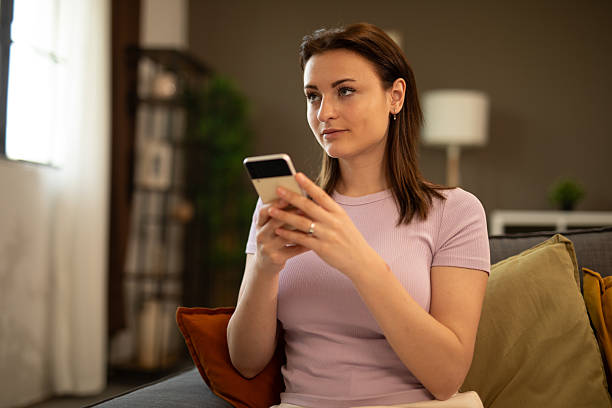 istock Young woman relaxing on sofa using smartphone at home. Stock image 2225126926