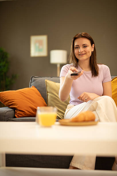 istock Young woman watching tv and having breakfast on the sofa. Stock image 2225127444