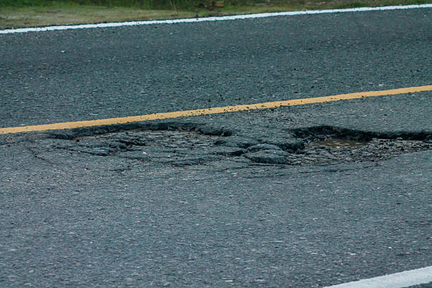 istock Old asphalt road with dangerously damaged asphalt that has potholes dangerous for the transit of motor vehicles 2225128293