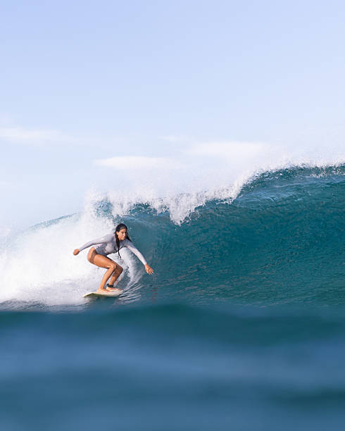 Lady surfing wave at remote island Indonesia