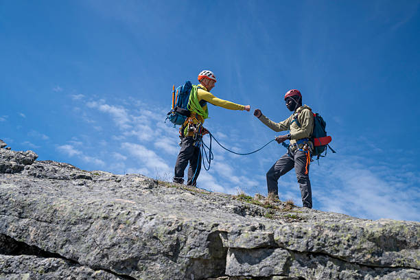 Climbing guide and guest celebrate with a fist bump on mountain top, British Columbia Coastal Ranges