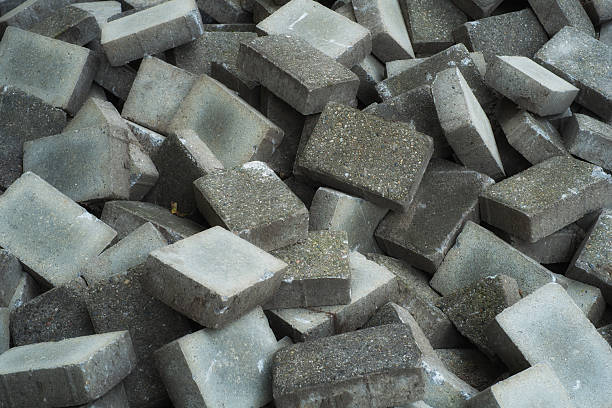 A heap of concrete building blocks displaying an intricate array of textures and patterns. These materials are commonly used in construction and paving, signifying urban development and functionality in architecture.